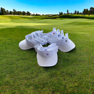 Ladies Golf Visor white cotton twill with adjustable velcro and contrast sweatband lined up on golf course grass.